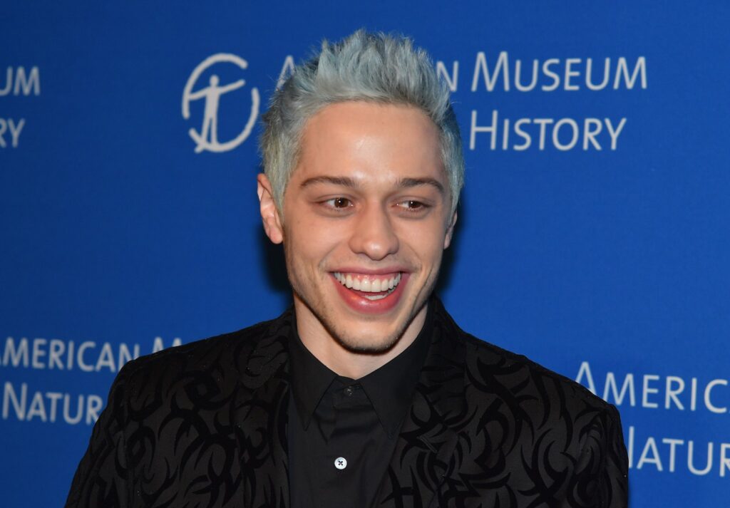 The image of Pete Davidson (Peter Michael Davidson) in a Show wearing black suit and having a smile on his face.